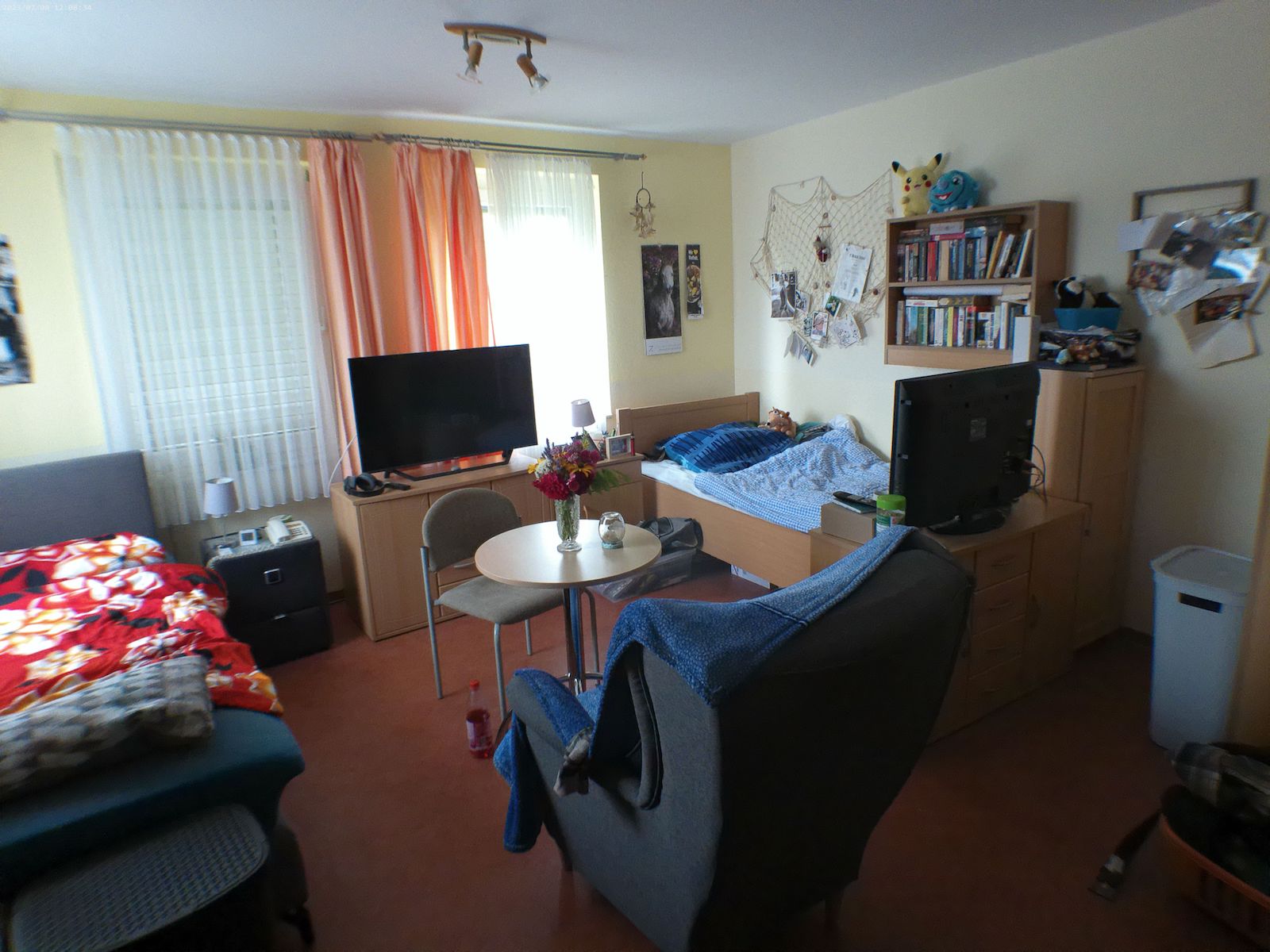 Ein Schlafzimmer wo zwei Leute drinnen schlafen können, in der mitte steht ein Sessel auf den Fernseher gerichtet.